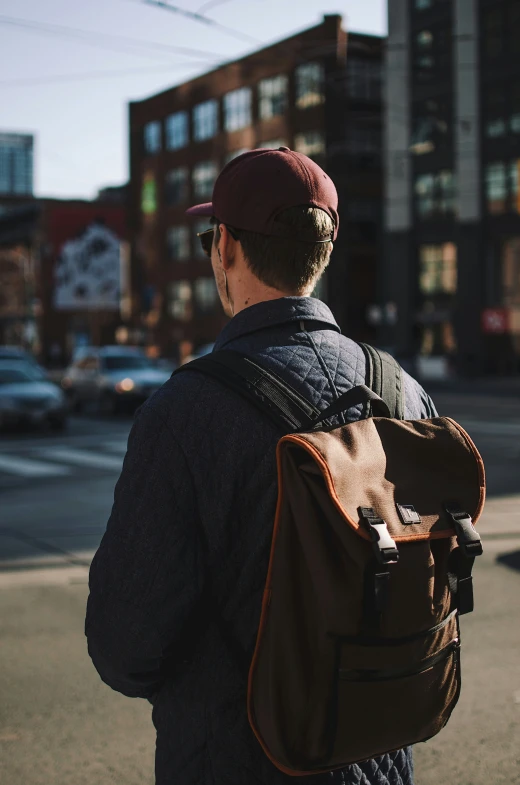 a man with a bag looking across the street at buildings