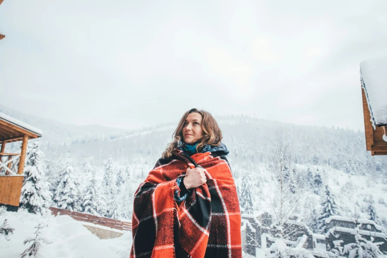 a woman standing under a blanket in the snow