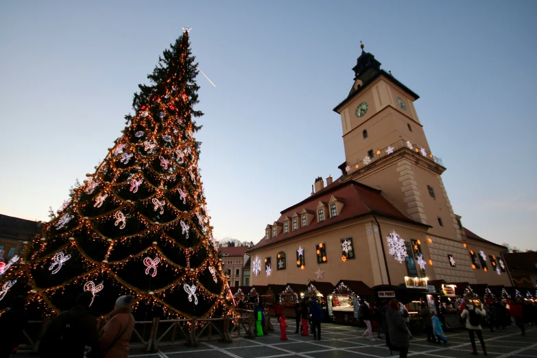 several people are gathered at the square around a christmas tree
