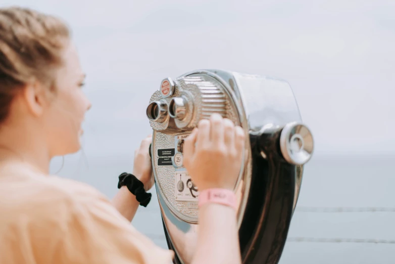 the woman is looking through the telescope lens