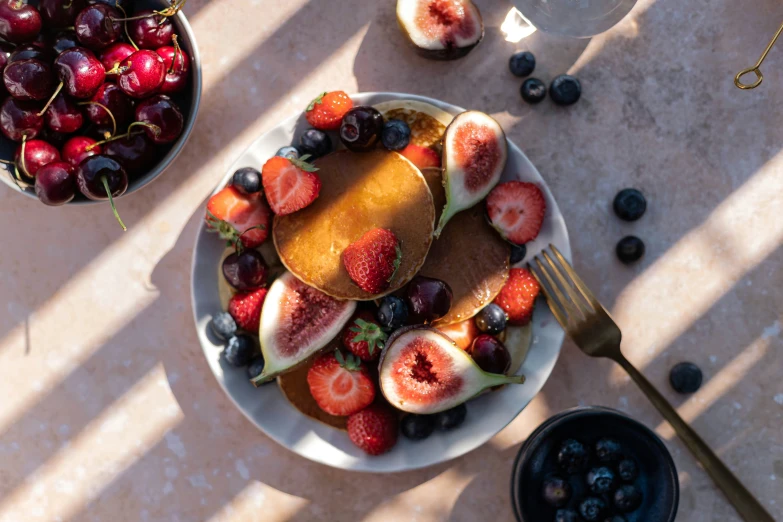 fruit platter with pancake topped with strawberries, blueberries and cherries