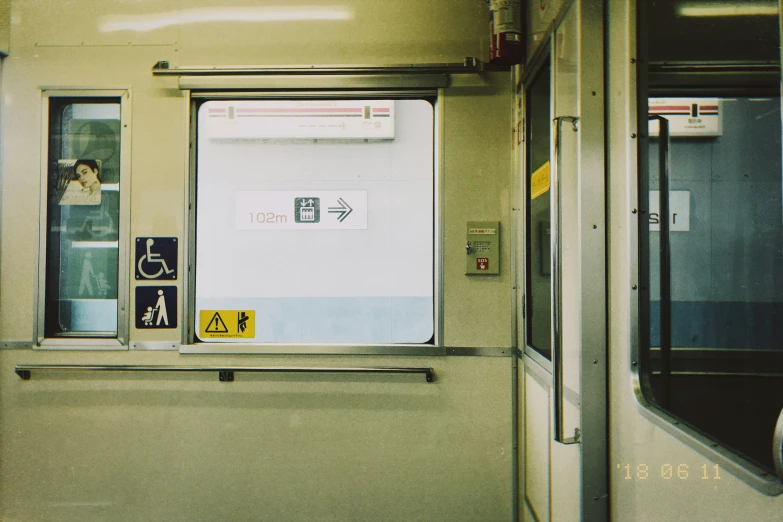 inside of a subway car with signage, window and door