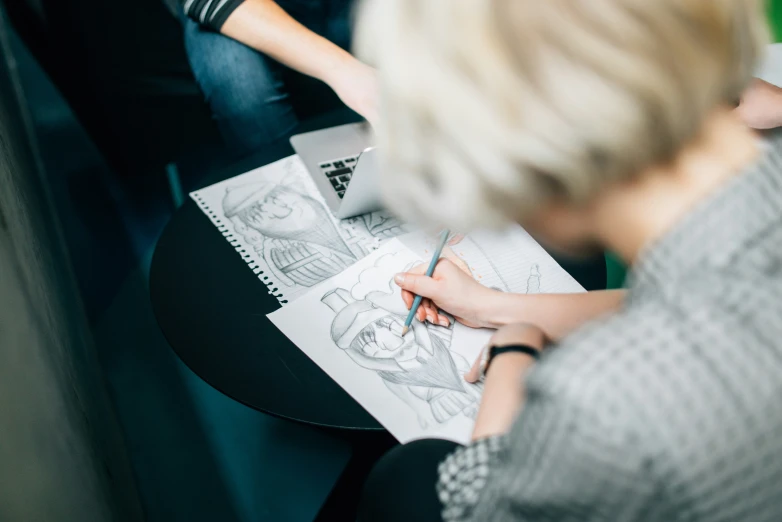 a woman sitting down doing drawing with her notebook