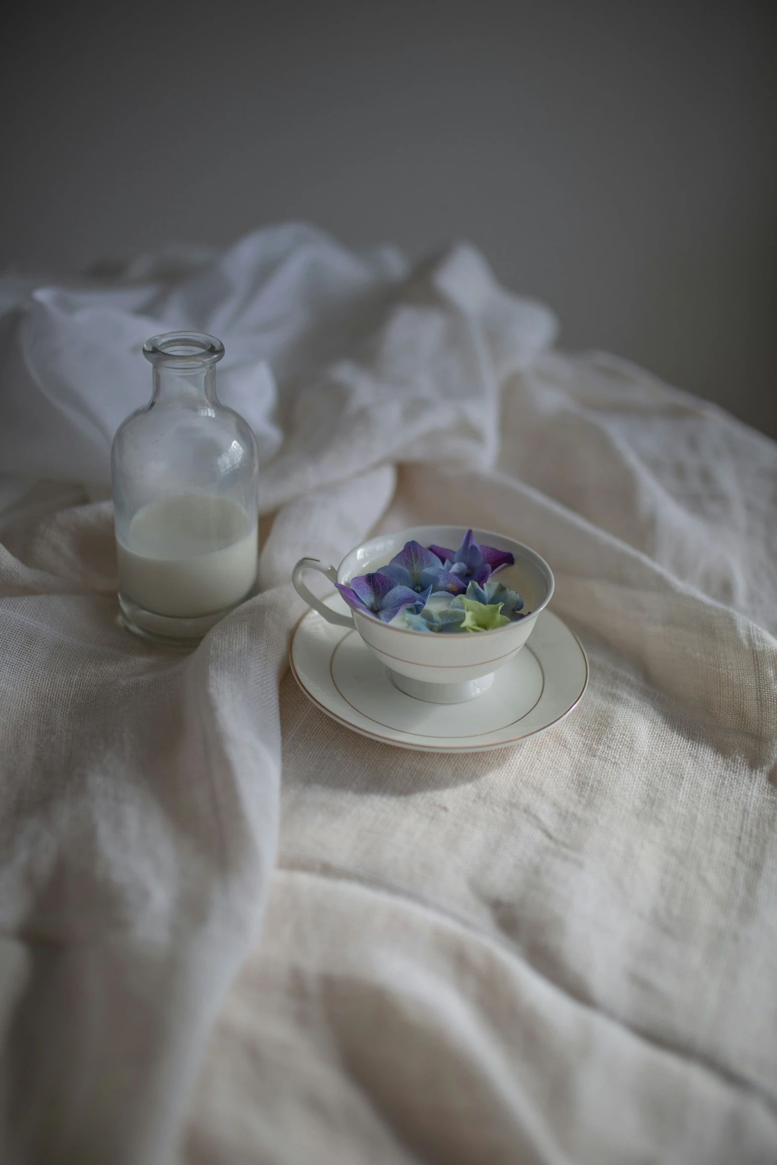 a table with flowers in it and a glass of milk