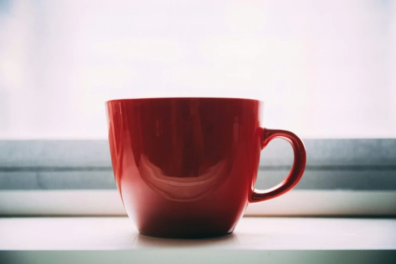 a red cup sitting on top of a windowsill