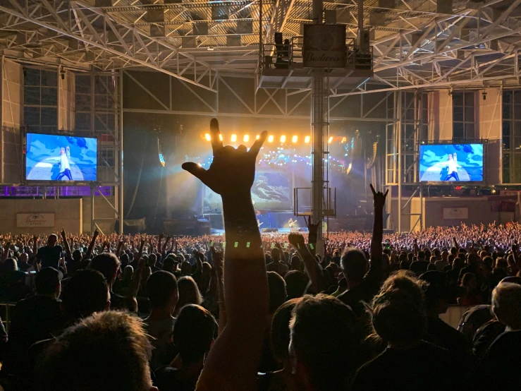 a man is reaching up into the air at a concert