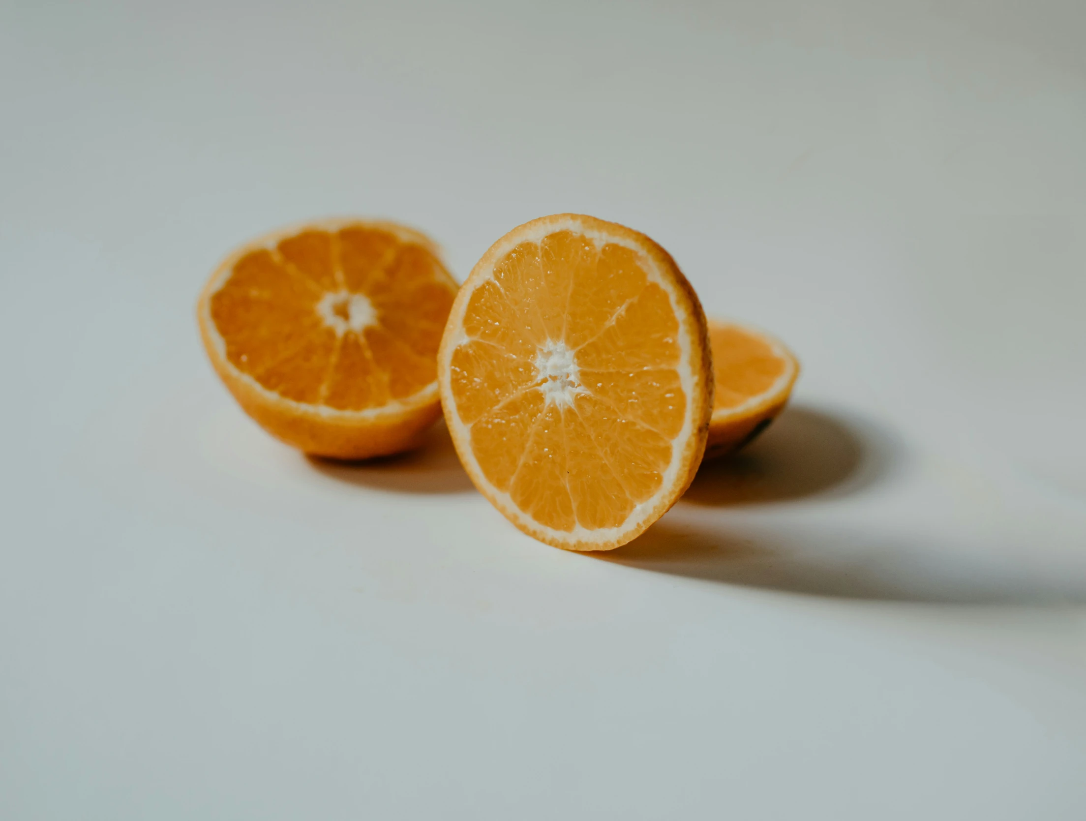 two halves of orange cut in half laying on a white table