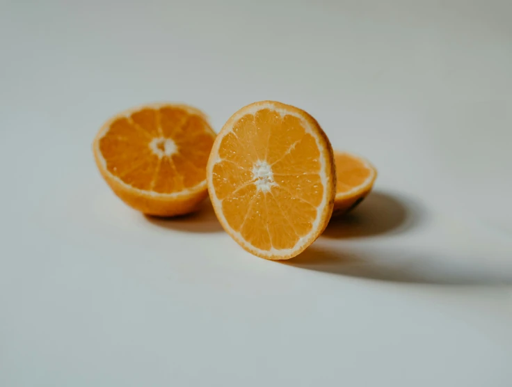 two halves of orange cut in half laying on a white table