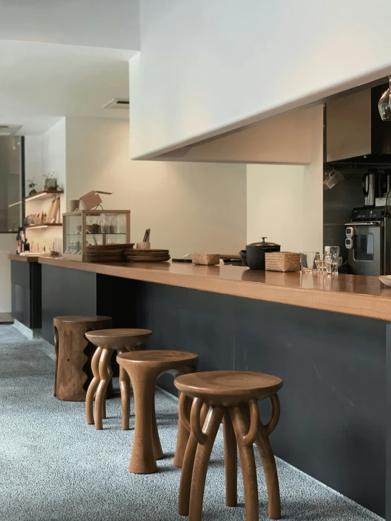 wooden stools are at the bar of this long kitchen