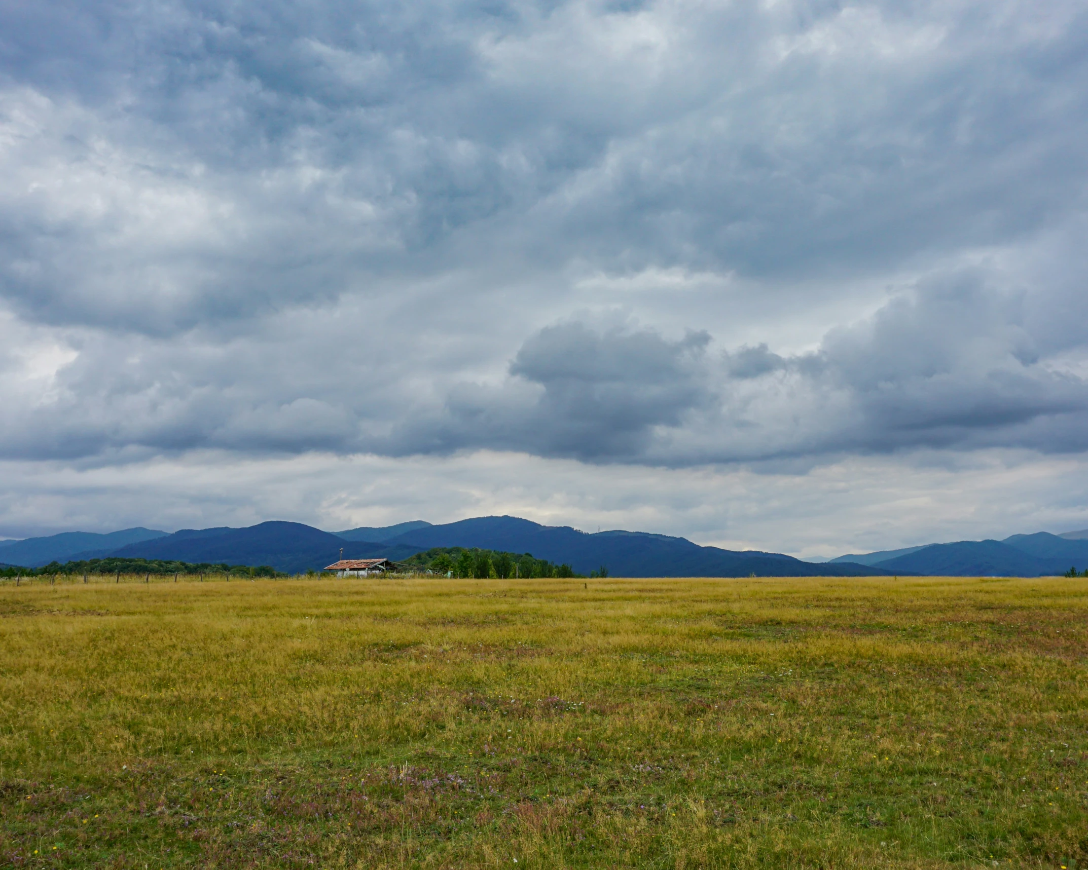 a big empty grassy field with mountains in the distance