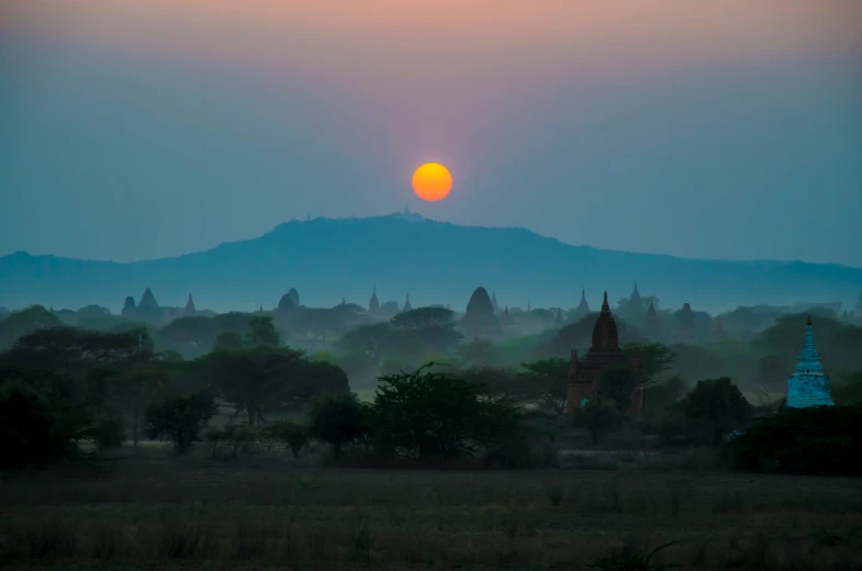 a hazy sunrise shines in the horizon over some type of town