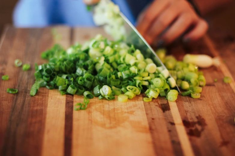 someone chopping onions on top of a wooden  board