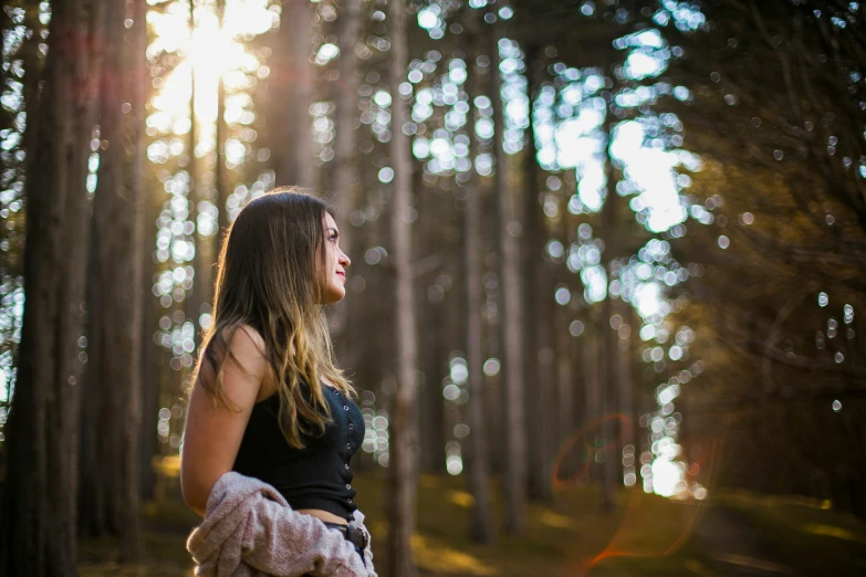 the young woman is standing outside in the woods