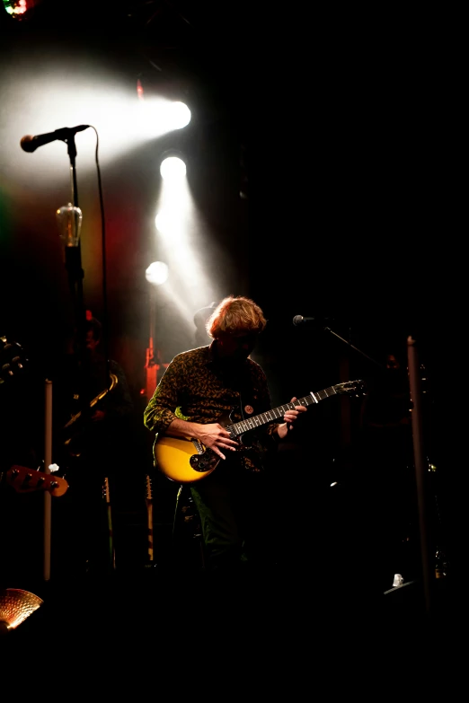 man playing guitar in front of three microphones