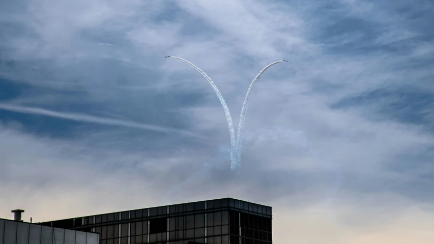 two airplanes flying high in the sky and trailing smoke