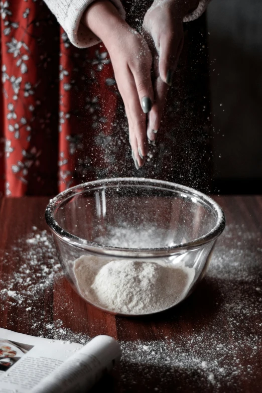 a woman is sprinkling flour in a bowl