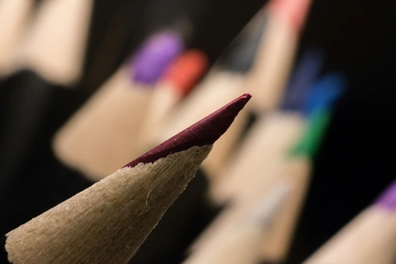 the tip of a pencil sticking out of a row of colored pencils