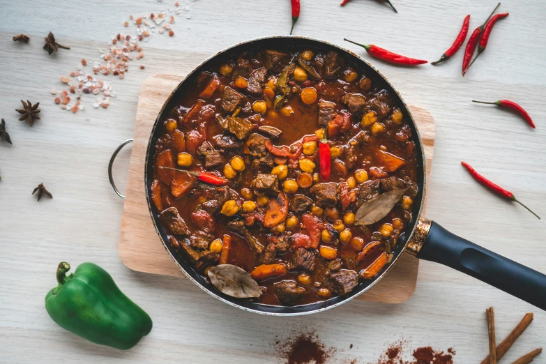 a pot filled with chili and some other food on a wooden board