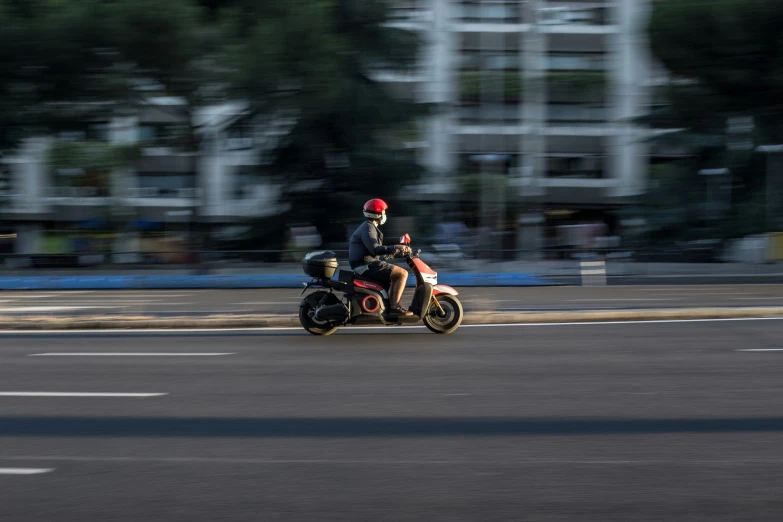 a man riding a motorcycle down a street next to a tall building