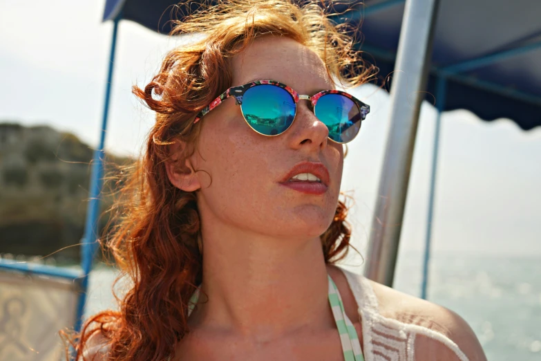 a young woman wearing colorful mirrored sunglasses on the water