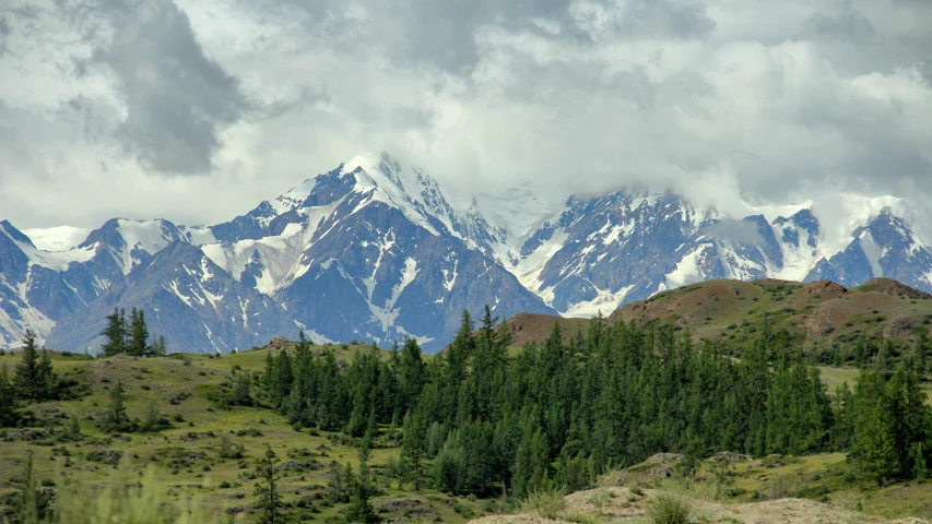 a view of mountains and clouds above some trees