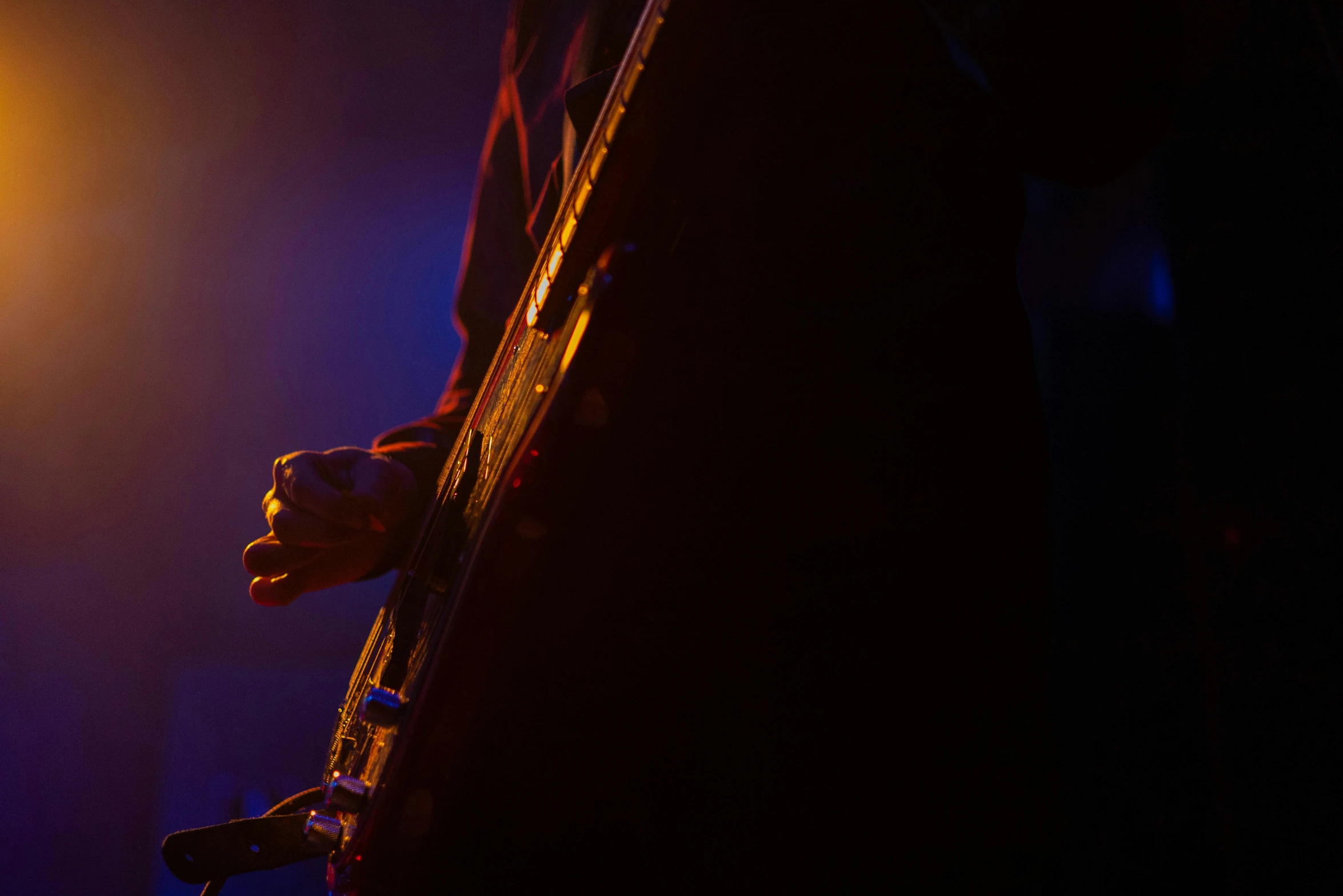 the silhouette of a person holding a guitar in the dark