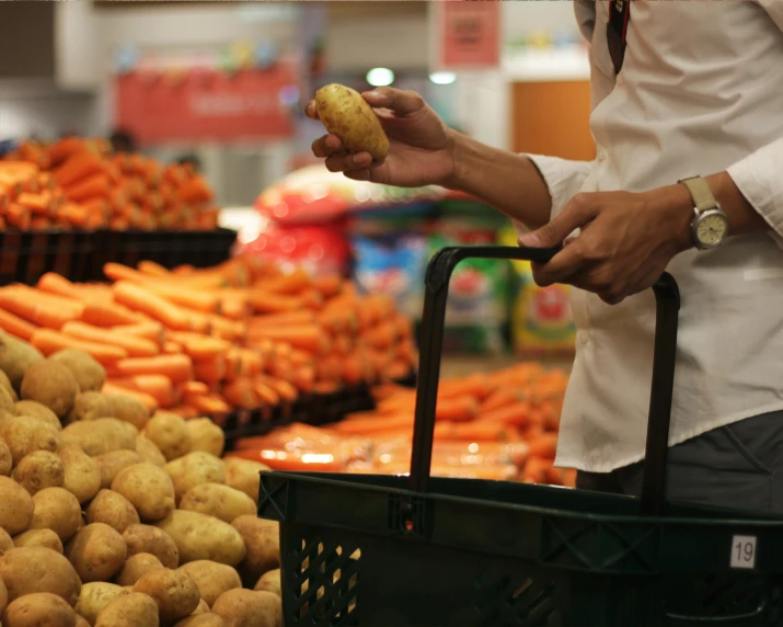 a woman standing in a produce aisle holding a doughnut