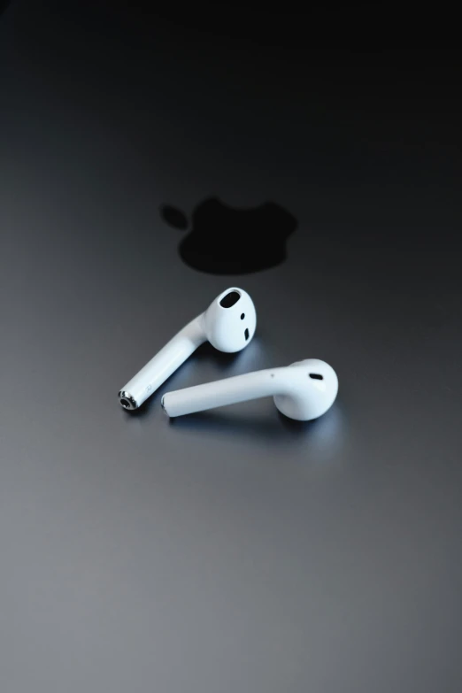 two white ear buds sitting on top of an apple logo