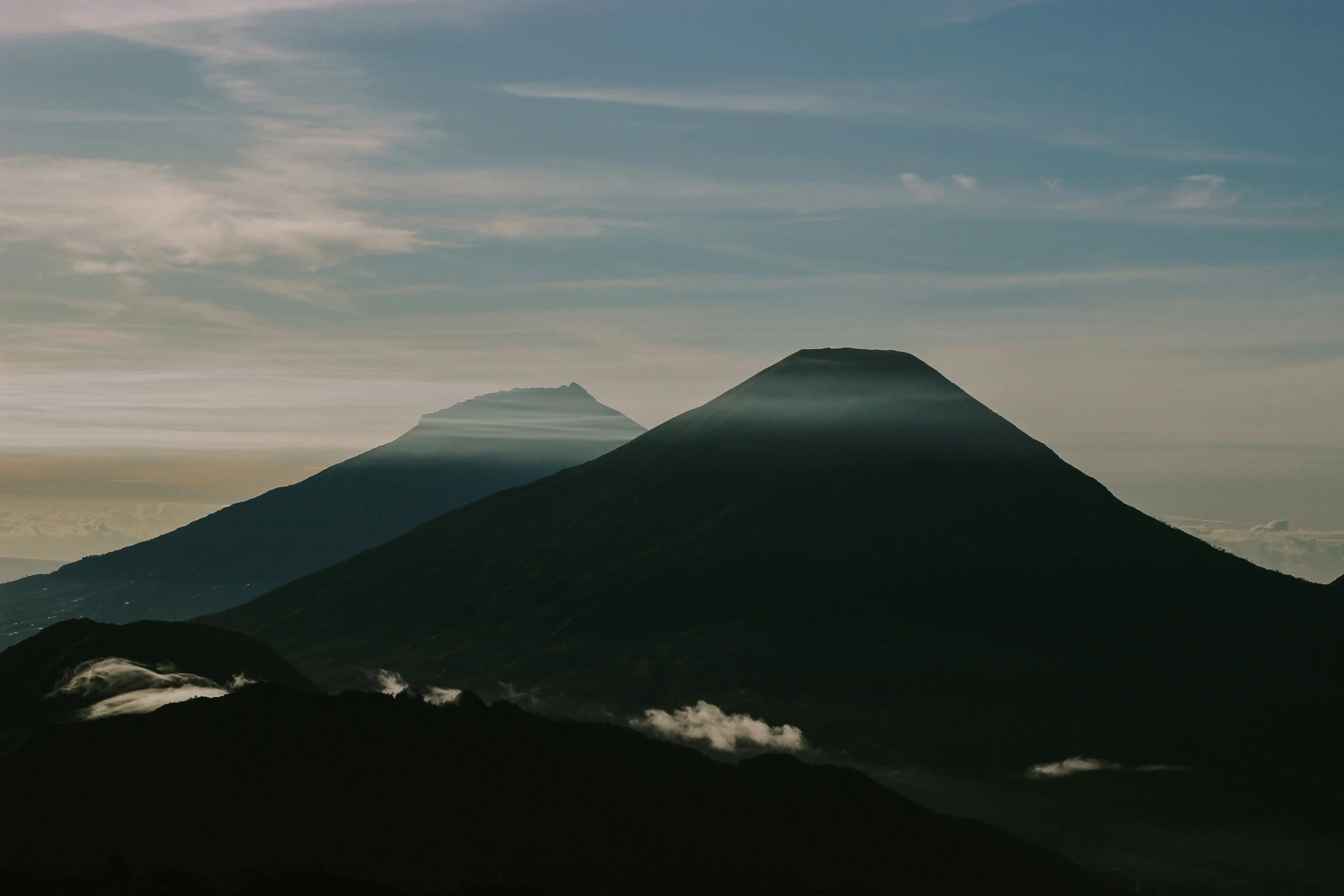 the top of a mountain, with sun shining in between them