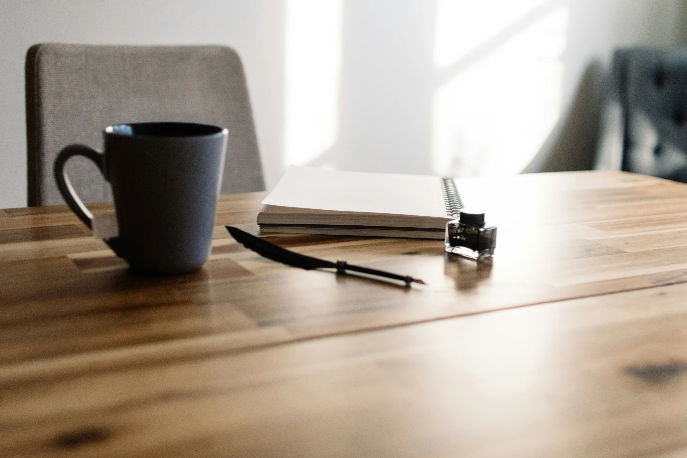 a coffee cup and notebook on top of a wooden table