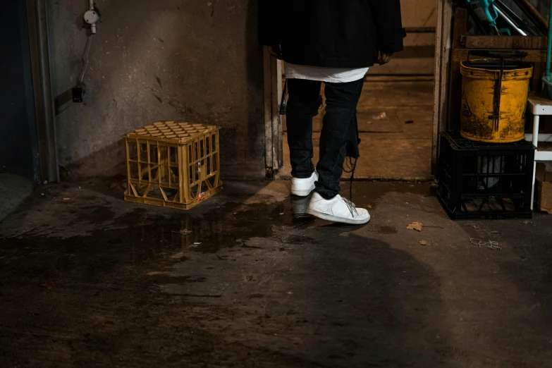 a person in white shoes stands next to crates