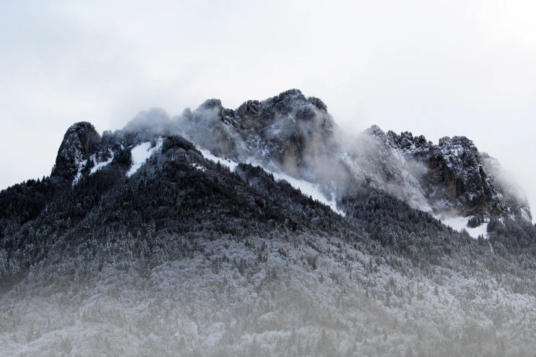 a cloudy view of a mountain covered in snow