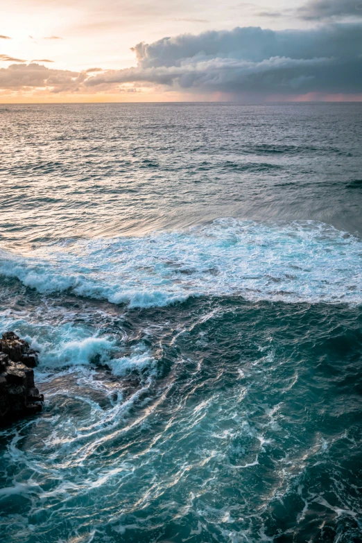 the ocean waves roll on rocks towards the shore