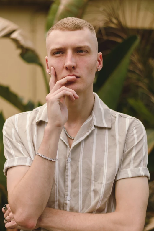 the man in the shirt poses with his hands near his mouth