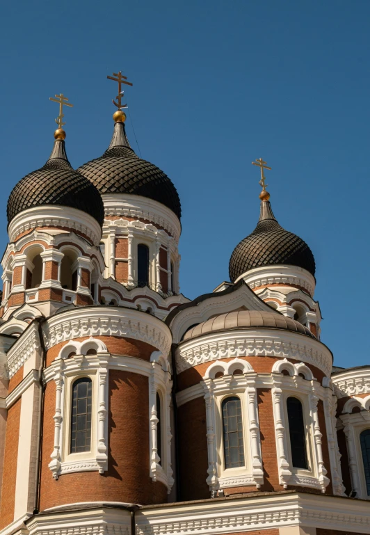 a tall red brick and white building with some crosses on it's domes