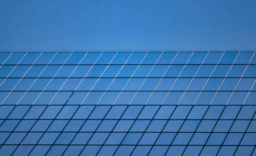 the side of a glass building with the top of an object hanging off