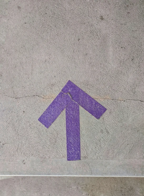 an arrow painted purple on a cement floor