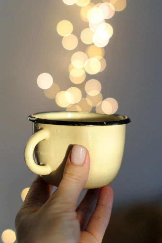 the person is holding their cup in front of a christmas tree