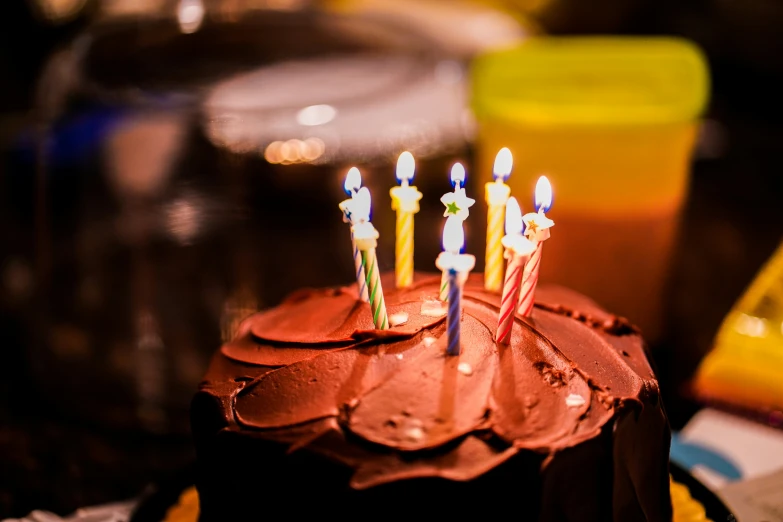 a small cake with chocolate icing and lit candles on top