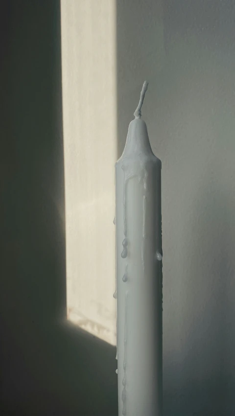 a candle is standing in front of a light window