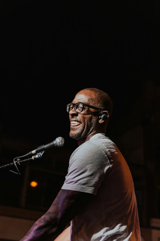 a man in glasses standing at a microphone