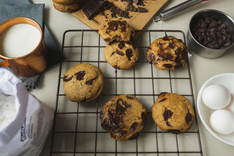 chocolate chip cookies cooling on a rack with eggs and milk