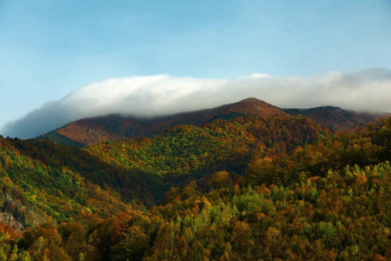 there is a hill in the distance that is under a cloud