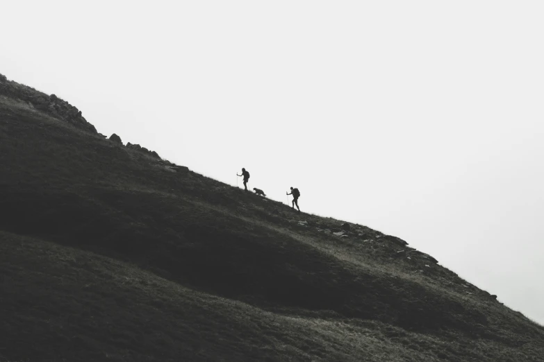 two people standing on top of a green mountain