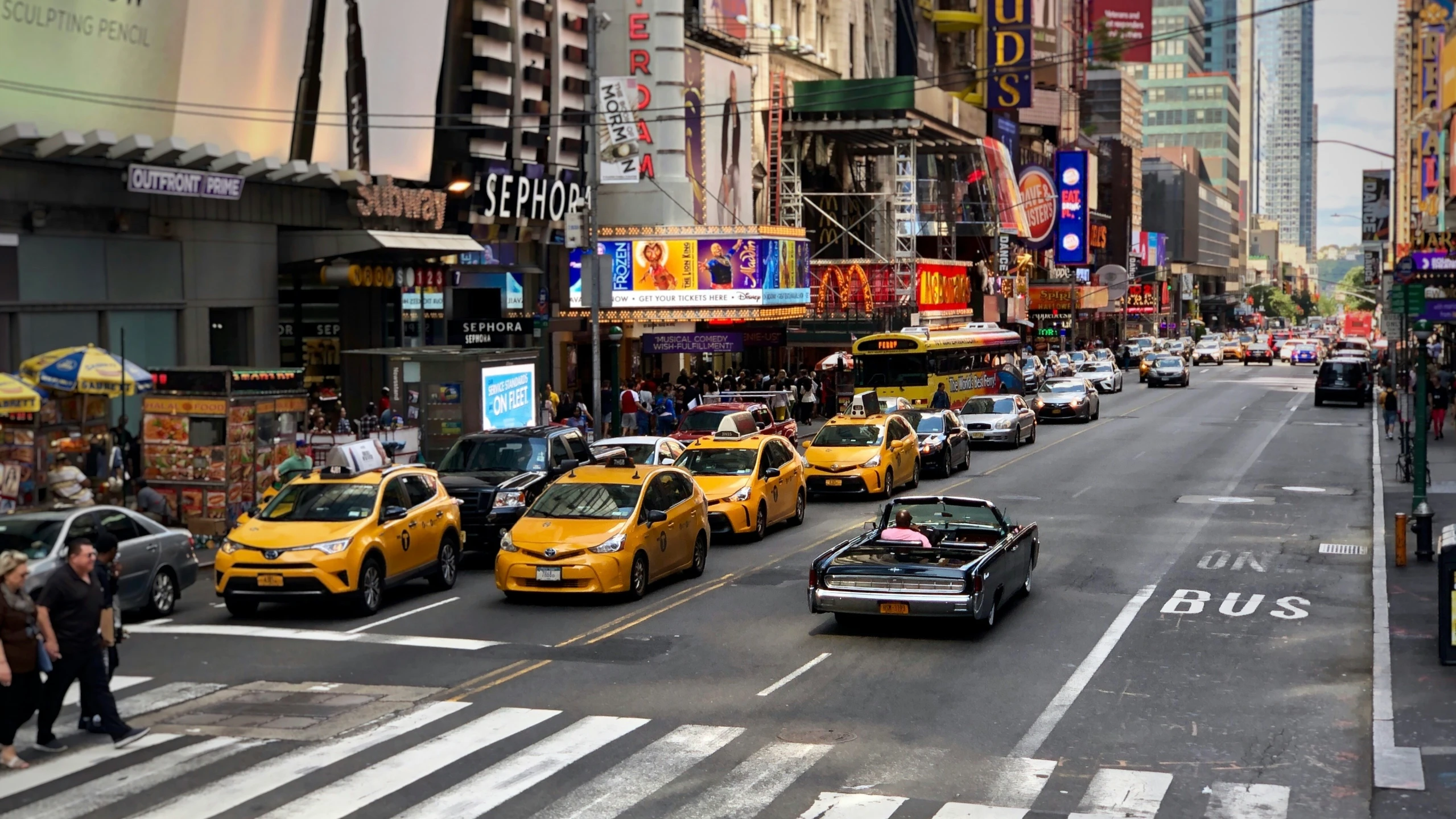 many cars traveling down the street near stores and buildings