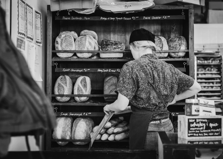 a man in the back of a bakery looking at bread
