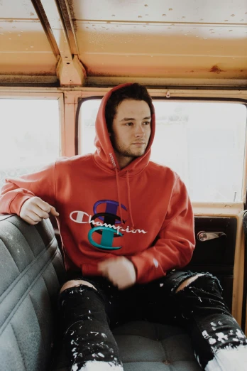 a man with hoodie sitting on seat inside a bus