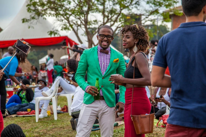 man in a green suit and some women at an outdoor party