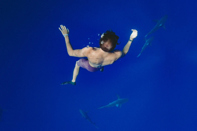 the man is swimming underwater in the deep blue water