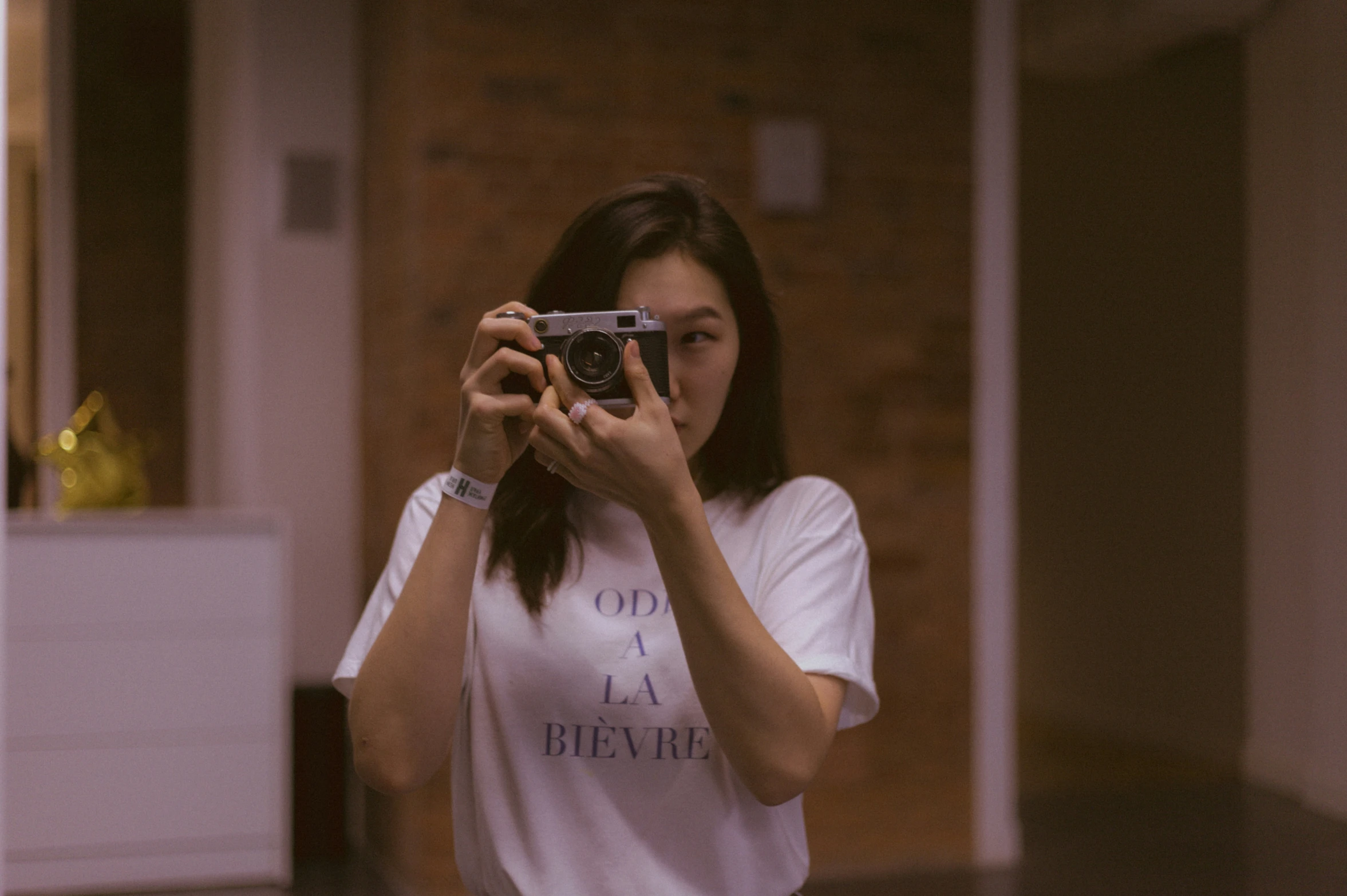 woman taking pograph in room with white t - shirt and brown tiled floor